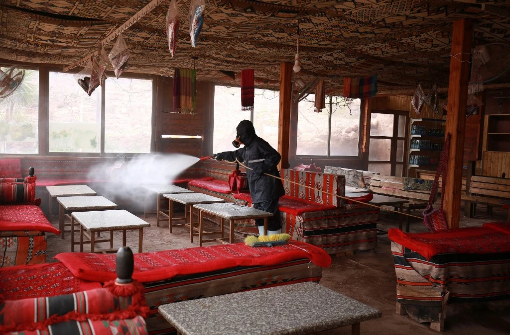 Above, a laborer sprays disinfectant in Jordan’s archaeological city of Petra on March 17, 2020, to prevent the spread of COVID-19. (AFP)