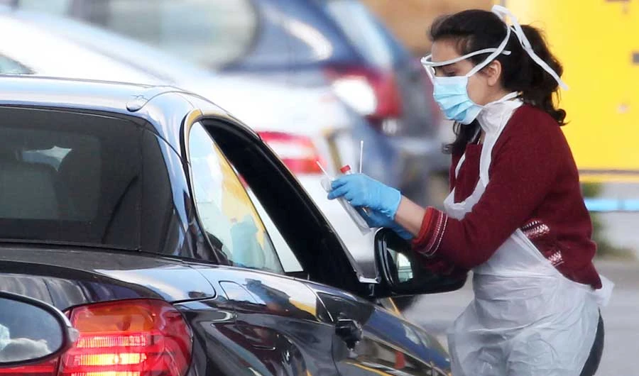 A medical staff member wearing gloves, eye protection and a face mask, tests an NHS worker for the novel coronavirus COVID-19 at a drive-in facility set up in the car park of an IKEA store in Wembley, north-west London. (AFP file photo)