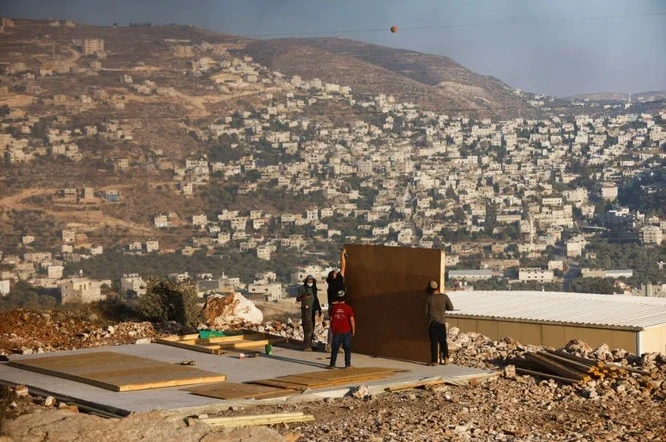Jewish settlers youths construct a structure in Givat Eviatar, a new Israeli settler outpost, near the Palestinian village of Beita in the West Bank on June 23, 2021. (REUTERS)
