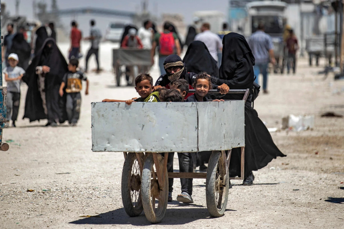 A young man pushes a cart with carrying children inside at the Kurdish-run al-Hol camp, which holds relatives of suspected Daesh militantss, in Hasakeh, Syria, on June 23, 2021. (AFP / Delil Souleiman)
