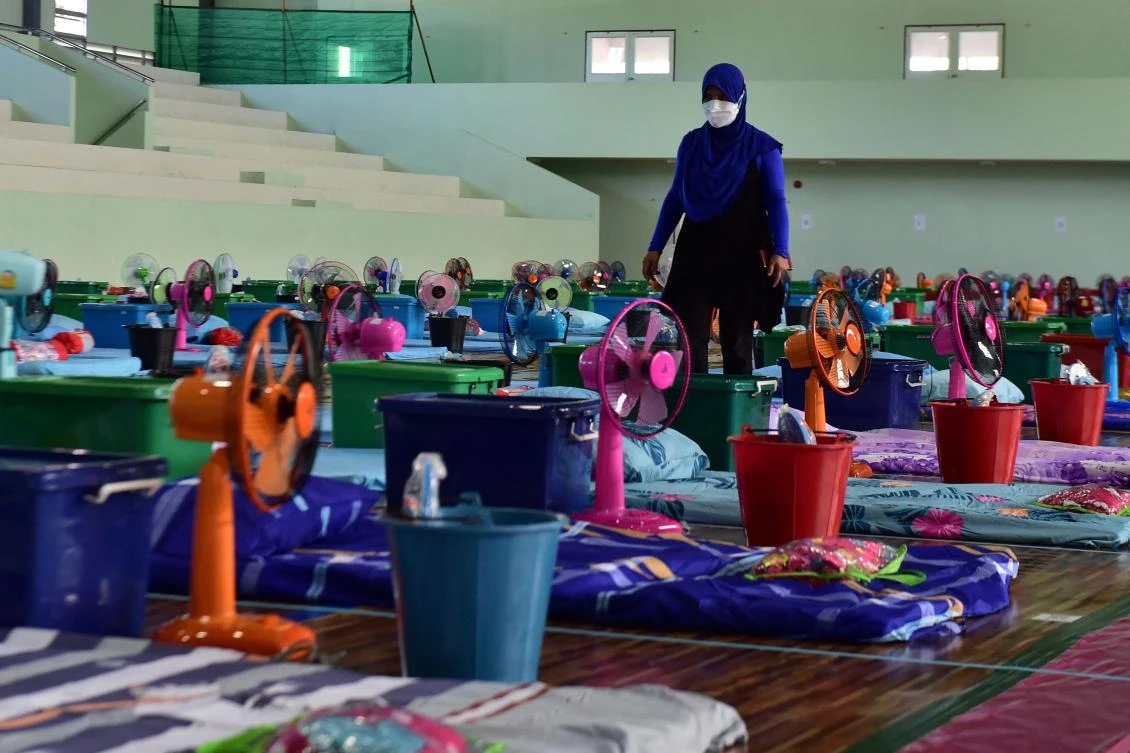 A staff prepares beddings at the gymnasium Narathiwat Rajanagarindra University that was converted as a field hospital facility for COVID-19 patients. (AFP)