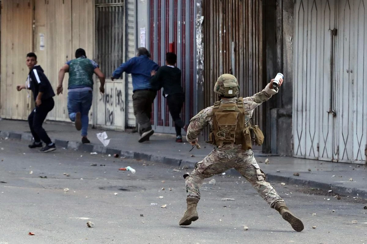 A Lebanese army soldier throws a tear gas canister towards anti-government protesters in Tripoli, Lebanon on Tuesday, April 28, 2020. (AP)