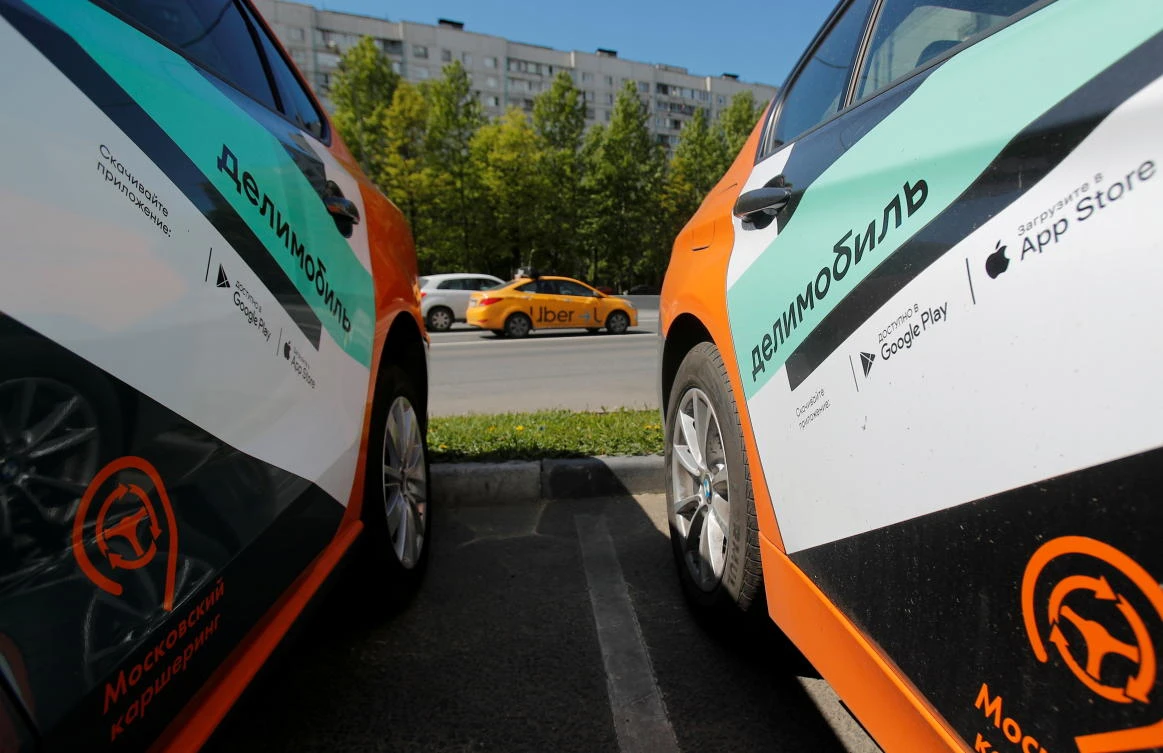 Taxi car drives by Delimobil branded vehicles amid the outbreak of the coronavirus disease (COVID-19) in Moscow. (Reuters)