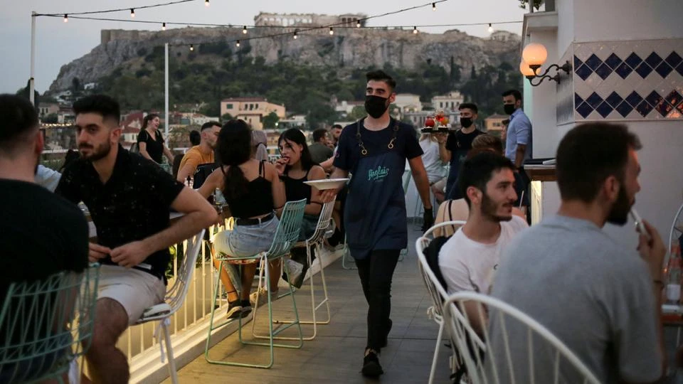 A waiter serves tables against the backdrop of the Parthenon on the Acropolis, Athens, Greece, August 1, 2020. (Reuters)