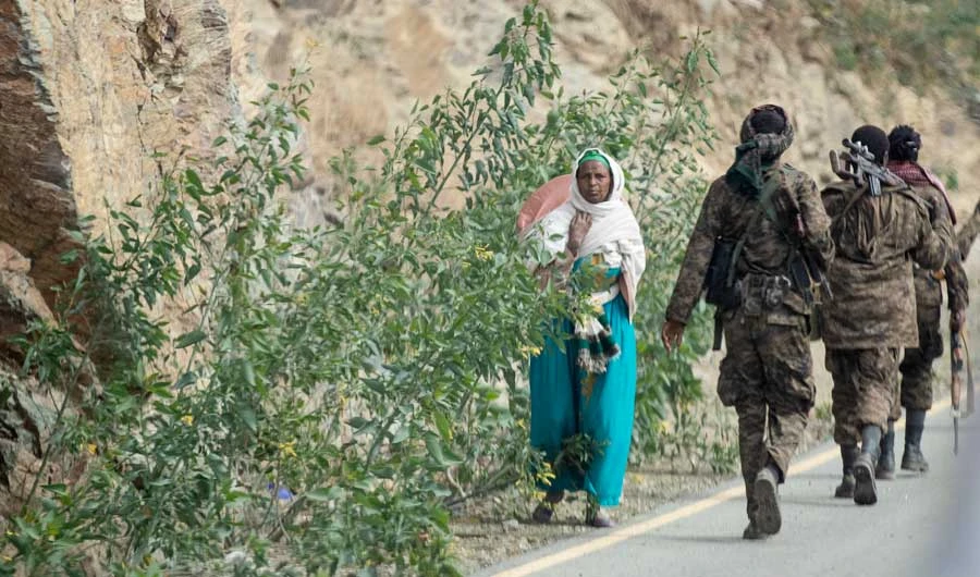 In this Friday, May 7, 2021 file photo, a woman walks past Ethiopian government soldiers by the side of a road north of Mekele, in the Tigray region of northern Ethiopia. (AP)