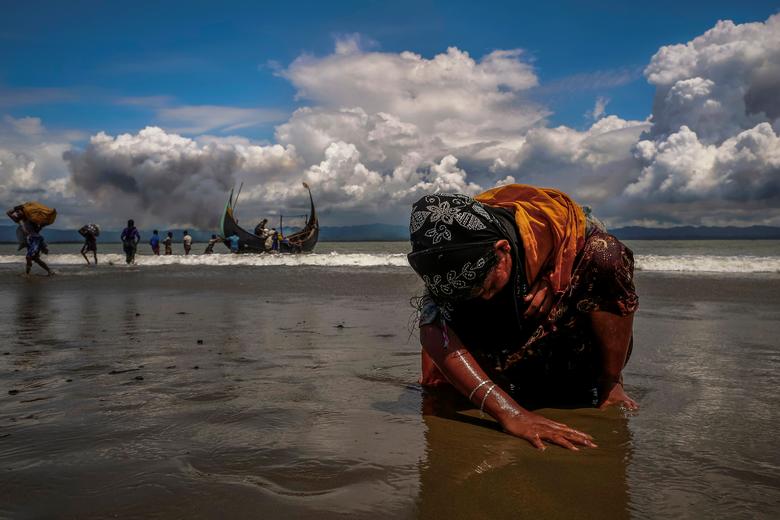 An exhausted Rohingya refugee woman touches the shore after crossing the Bay of Bengal, Shah Porir Dwip, Bangladesh, Sept. 11, 2017. (Reuters)