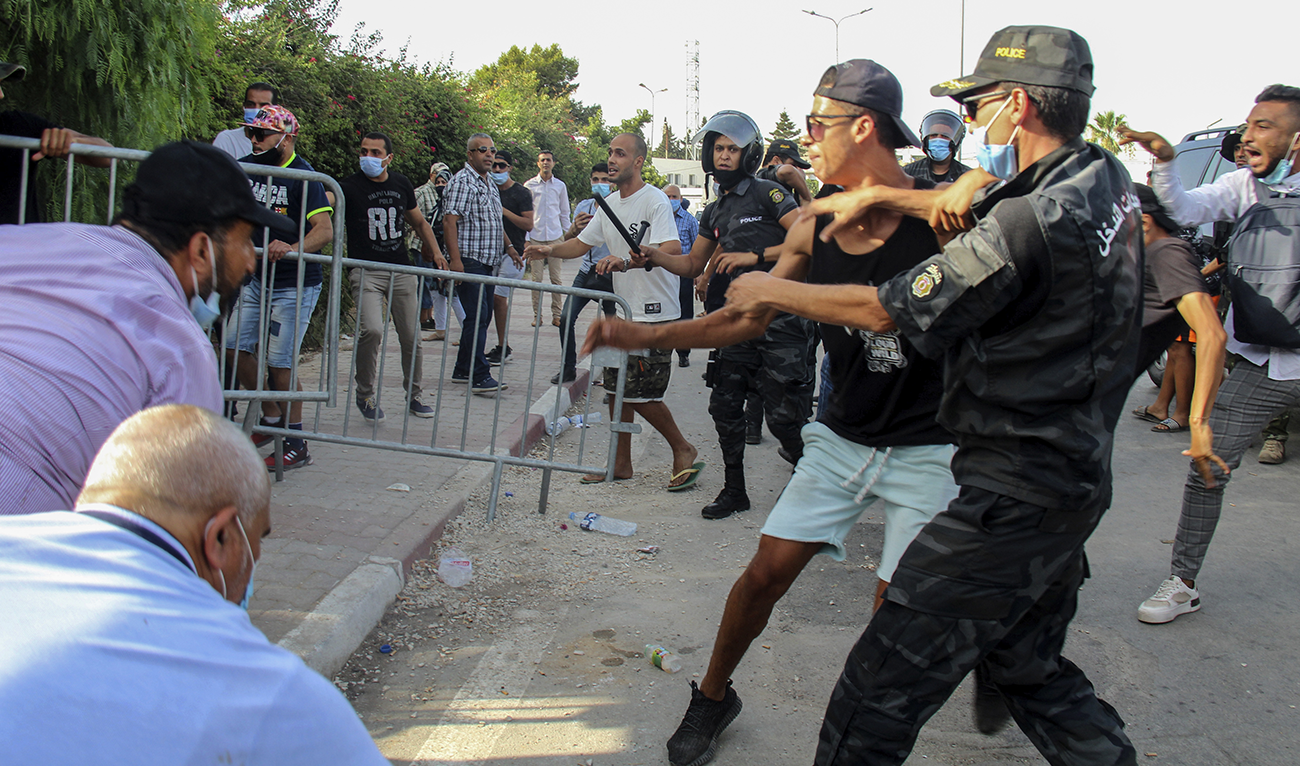 Tunisian police officers scuffle with demonstrators as they gather outside the parliament in Tunis, Tunisia, Monday, July 26, 2021. (AP)