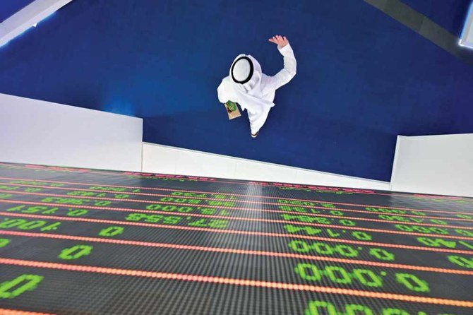 A trader walks underneath stock display board at the Dubai Stock exchange. Islamic finance has become a $2 trillion business over the past two decades, covering everything from bonds to buying a car. (AFP file photo)