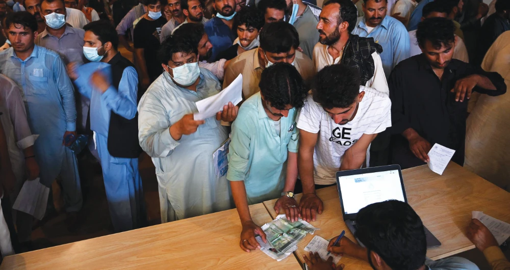 People including overseas Pakistani workers who want to fly to the Middle East register before receiving a dose of the Pfizer COVID-19 vaccine at a vaccine center. (AFP)