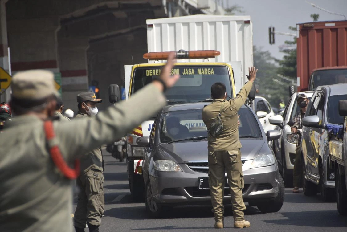 Officials turn back vehicles at the border with Jakarta in Bekasi, West Java on July 3, 2021, as Indonesia launches a partial lockdown in the capital. (AFP)