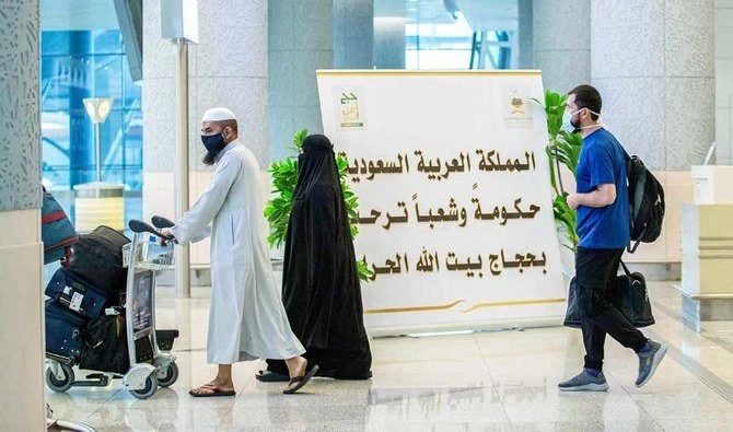A handout picture provided by the Saudi Ministry of Media on July 25, 2020, shows travelers walking with luggage past a welcome sign at the Red Sea coastal city of Jeddah's King Abdulaziz International Airport. (AFP)
