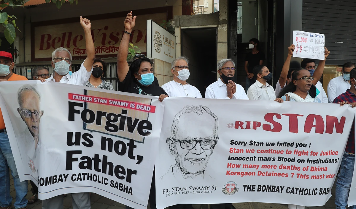 People hold banners and shout slogans during a prayer meeting for Father Stan Swamy outside a church in Mumbai, India, Tuesday, July 6, 2021. (AP)