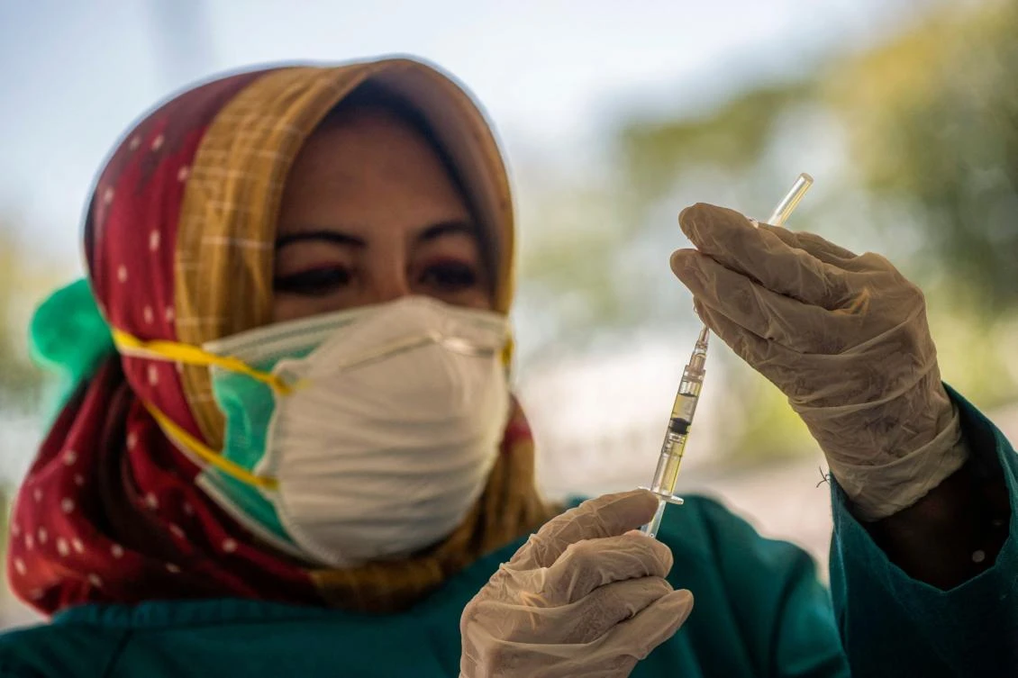 A doctor prepares to give the Sinovac Covid-19 coronavirus vaccine at a makeshift mass vaccination clinic on a football field in Surabaya. (AFP)