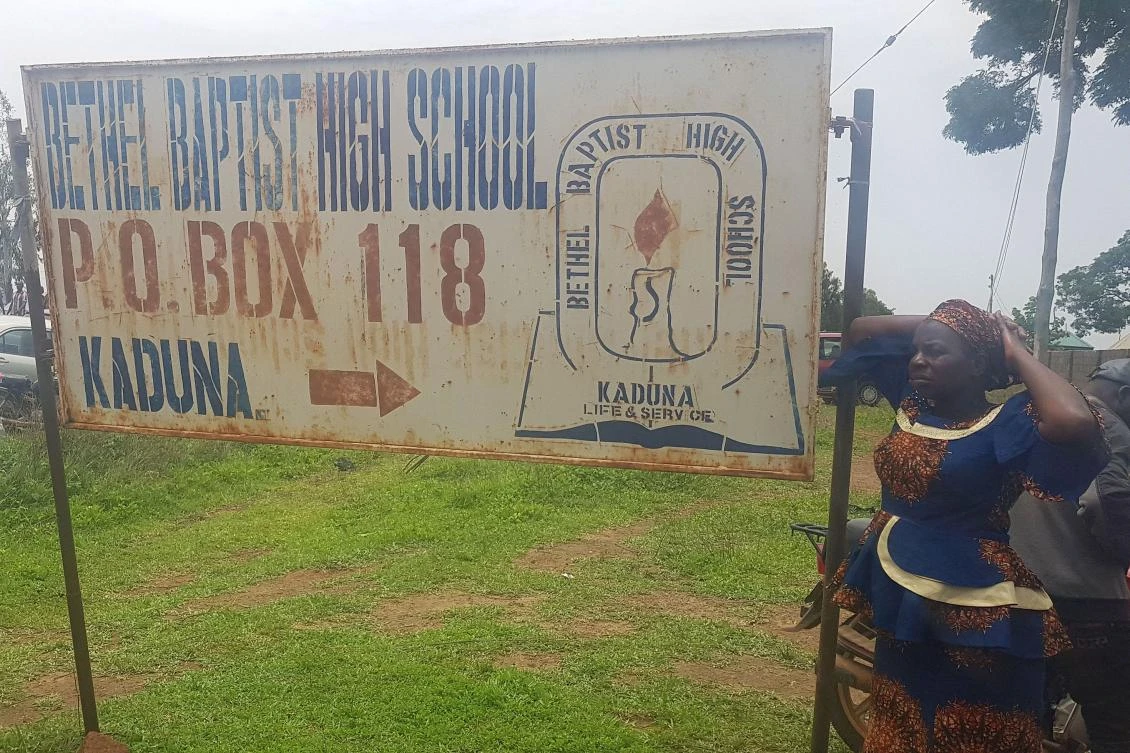 Parents stand beside the signpost of Bethel Baptist School where 140 boarding students were kidnapped by bandits in Kaduna, northwestern Nigeria, on July 5, 2021. (AFP)