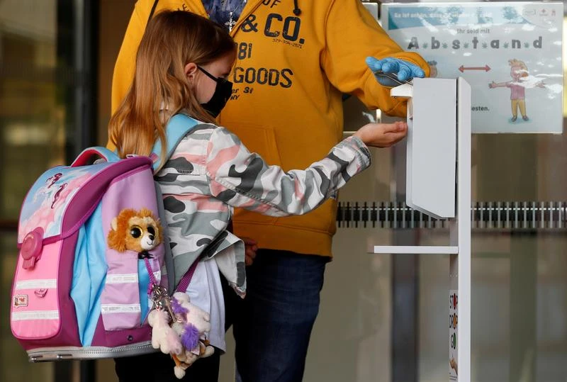A child wearing a protective face mask disinfects her hands as she arrives at a primary school in Brunn am Gebirge, Austria, May 18, 2020. (Reuters)