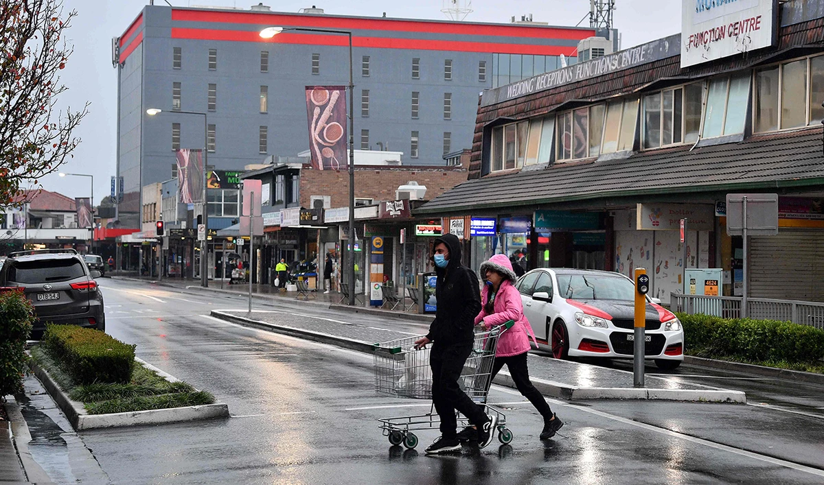 A couple make their way to a supermarket for last minute shopping ahead of new Covid-19 restrictions in the Fairfield suburb of Sydney on July 9, 2021. (AFP)