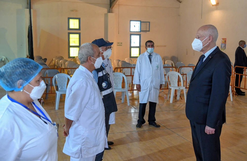 Tunisian President Kais Saied greets medical workers as he arrives to receive a dose of a COVID-19 vaccine, in Tunis. (AFP/Tunisian presidency Facebook page)