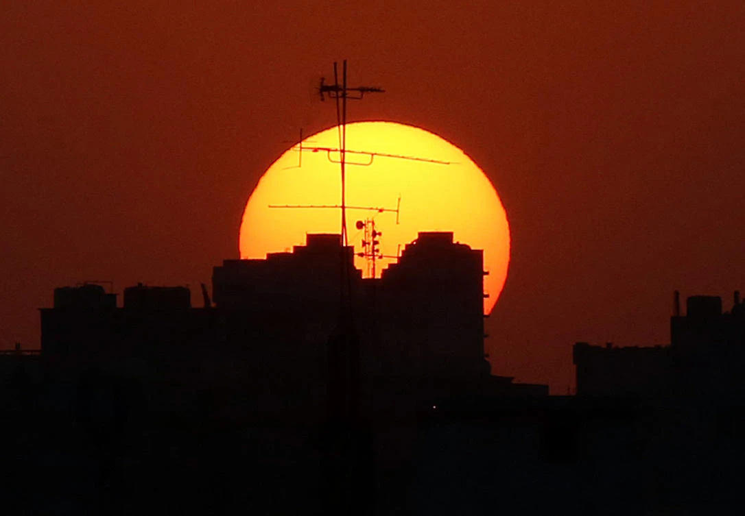 The sun sets behind buildings in Kuwait City. (AFP)