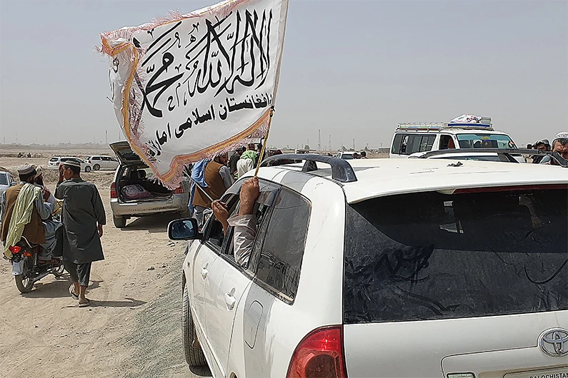 People wave a Taliban flag as they drive through the Pakistani border town of Chaman on July 14, 2021. (AFP)