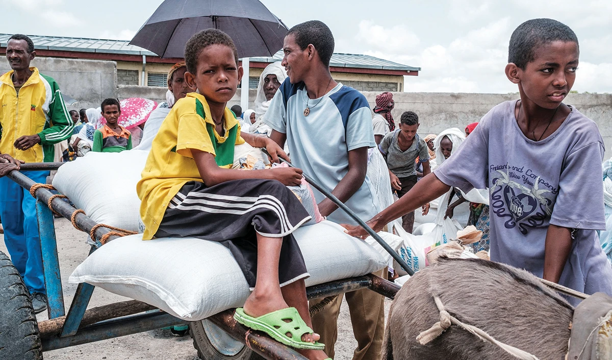 Children wait next to sacks of wheat at a food distribution point near the village of Baker, 50 km southeast of Humera, in the Tigray Region of Ethiopia. (File/AFP)