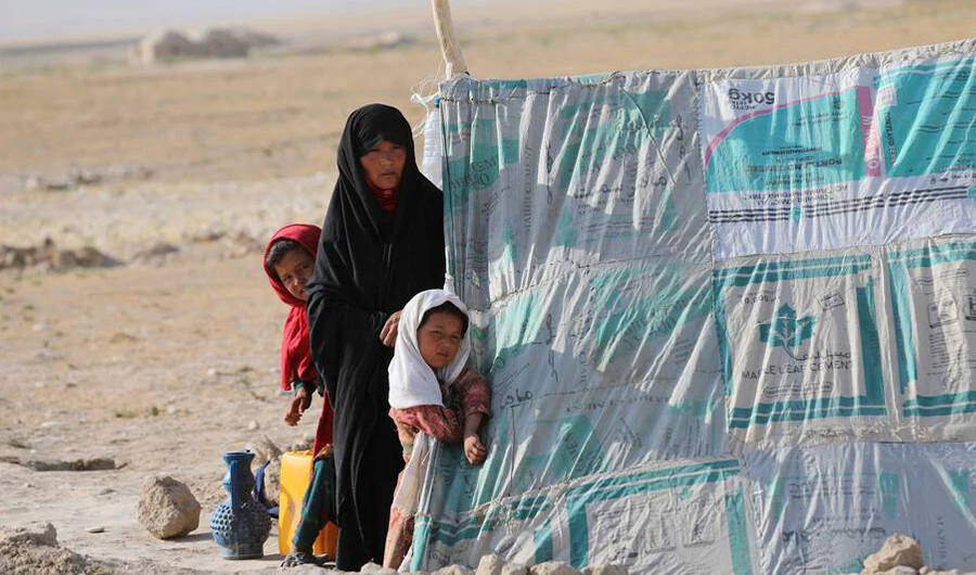 An internally displaced Afghan woman stands with her daughters in front a makeshift tent in a camp on the edge of the city of Mazar-e-Sharif, northern Afghanistan, Thursday, July 8, 2021. (AP)