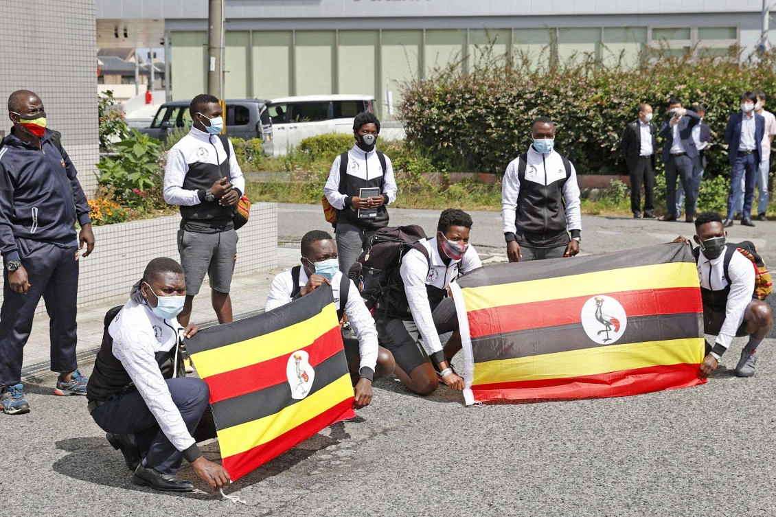 Ugandan Olympic delegation members pose with their national flags on arrival in Izumisano city, Osaka. A Ugandan athlete was reported missing by local officials Friday. (AP)