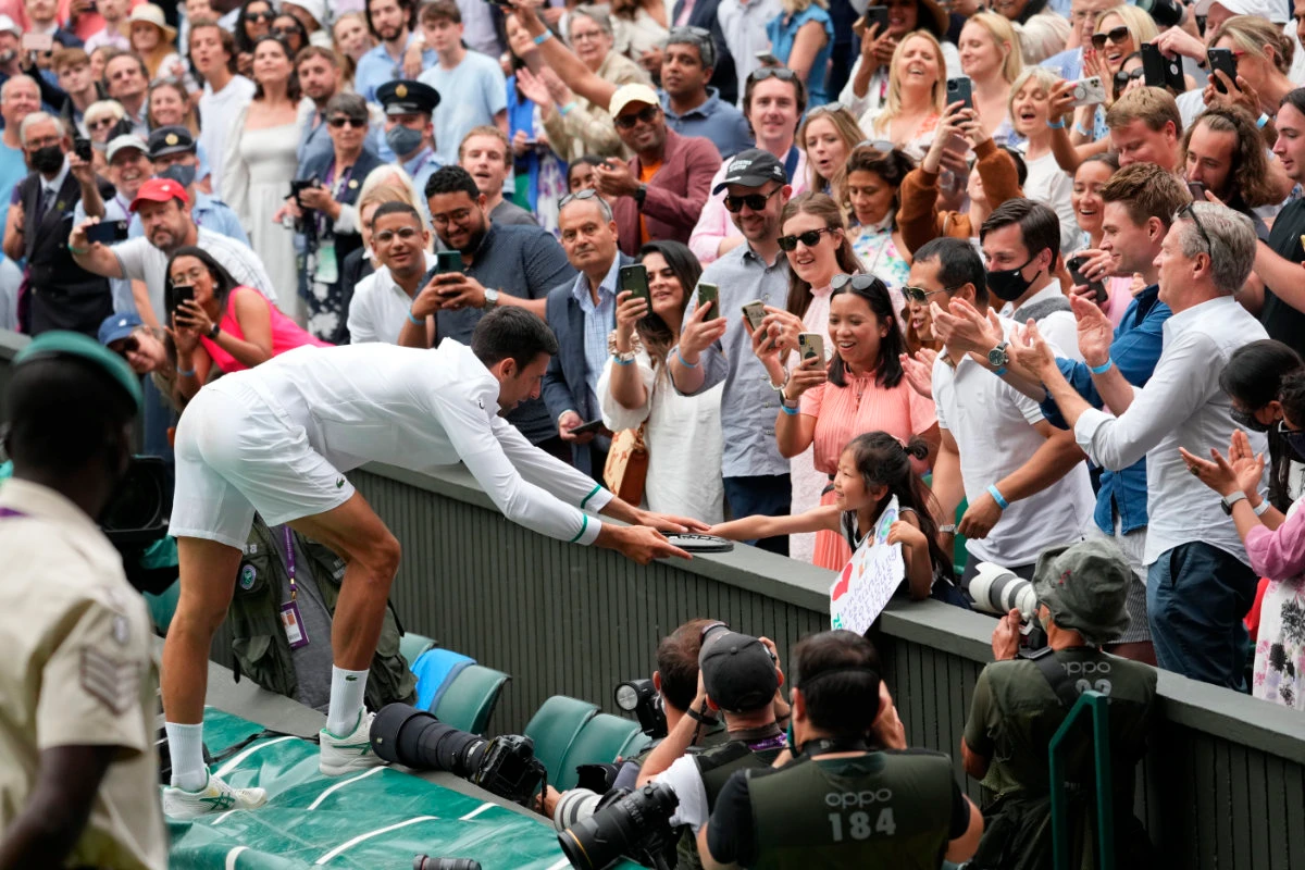 Novak Djokovic presents his tennis racquet to a young fan after winning the men's singles final of the Wimbledon Tennis Championships in London on July 11, 2021. (AP file photo)