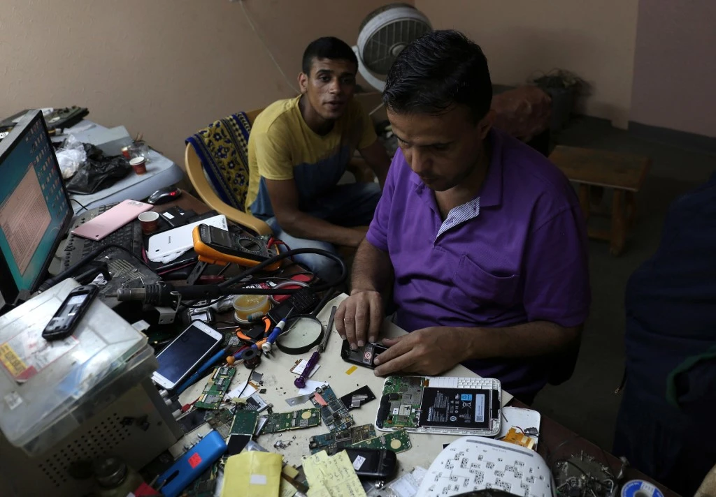 A picture taken on July 31, 2017 shows a Palestinian man working at a mobilephone repair shop during the few hours of mains electricity supply they receive every day, at Rafah refugee camp in the southern Gaza Strip. (File/AFP)