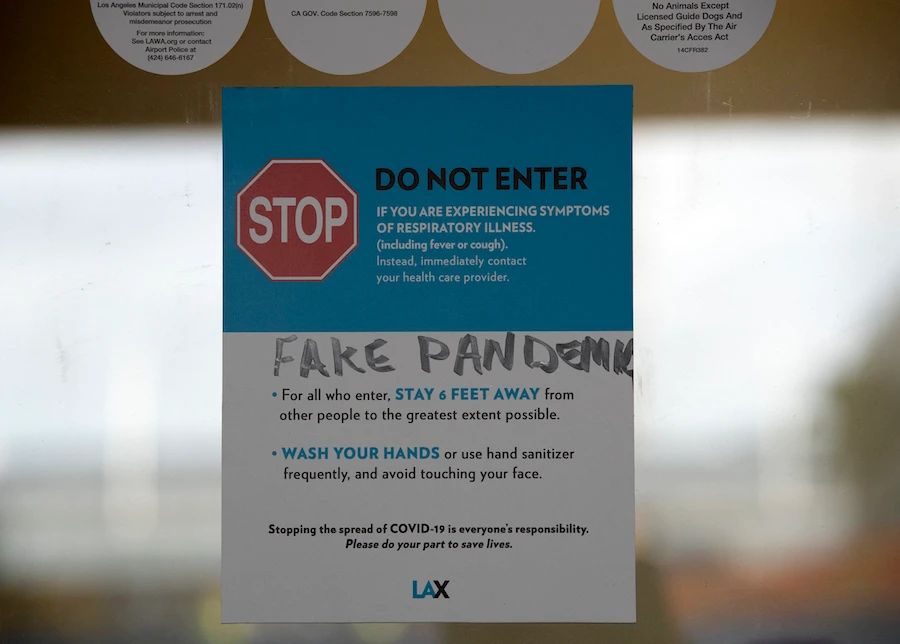 A sign about stopping the spread of COVID-19, the words "fake pandemic" written on it, is posted at Los Angeles International Airport (LAX) during the outbreak of the novel coronavirus. (File/AFP)