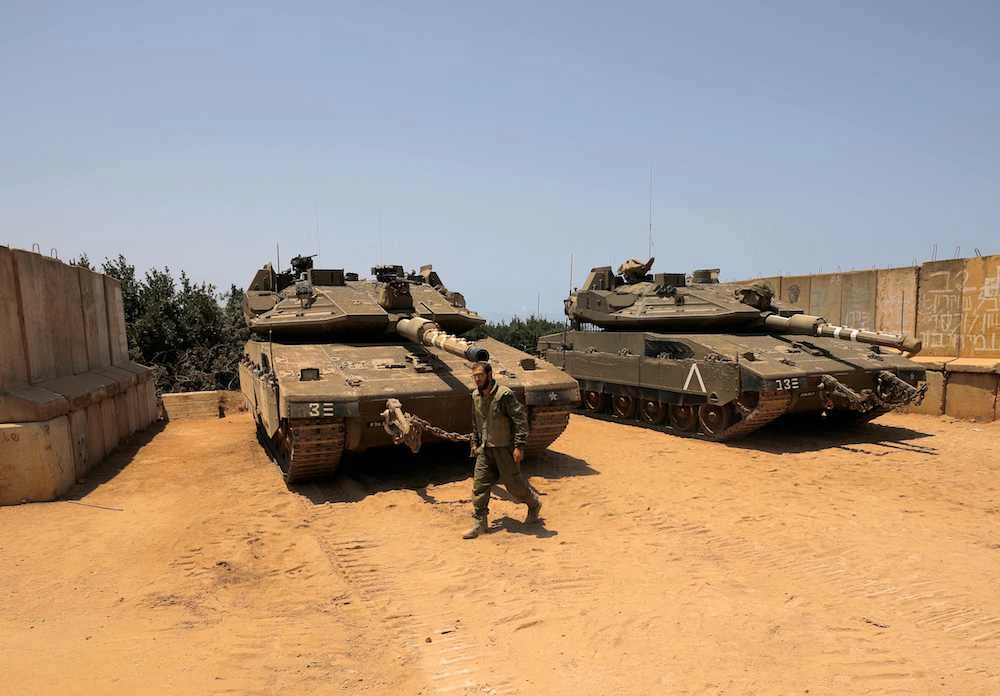 An Israeli soldier walks past tanks positioned near the northern Israeli settlement of Shtula along the border with Lebanon. (AFP)