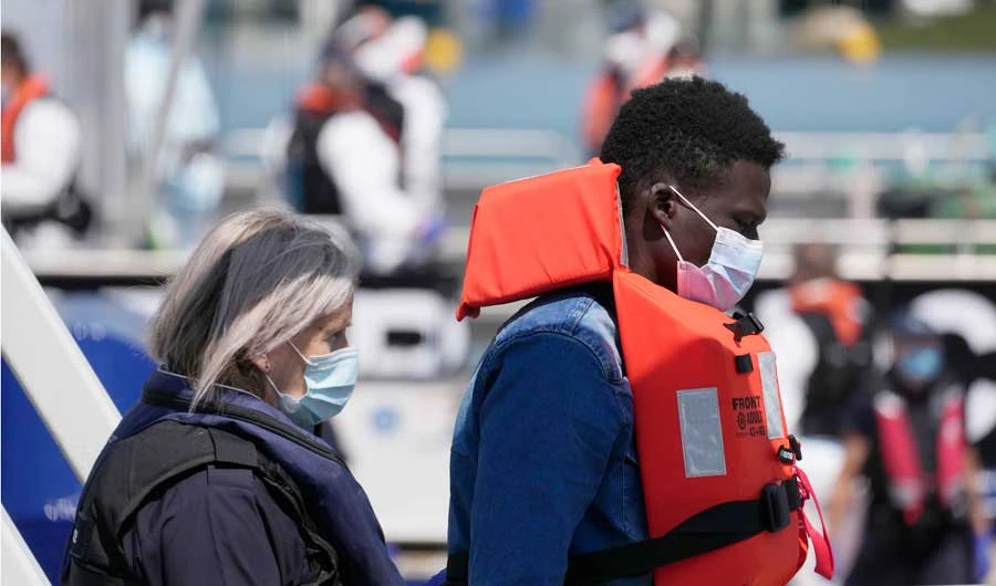 A man thought to be a migrant who made the crossing from France is escorted along a walkway after disembarking from a British border force vessel, in Dover, south east England, Thursday, July 22, 2021. (AP)