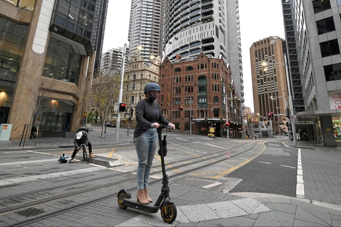A girl powers her electric scooter through the quiet central business district of in Sydney on 23, 2021, amid a coronavirus outbreak that state leaders said has become a "national emergency". (AFP)