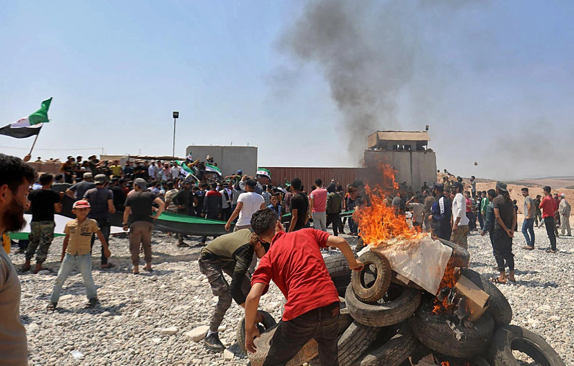 Syrians burn tyres as they protest in front of a Turkish military outpost during a demonstration against Turkey's perceived inaction over the latest Syrian regime attacks, in the town of Maataram near Ariha in the rebel-held northwestern Idlib province, on July 23, 2021. (File/AFP)