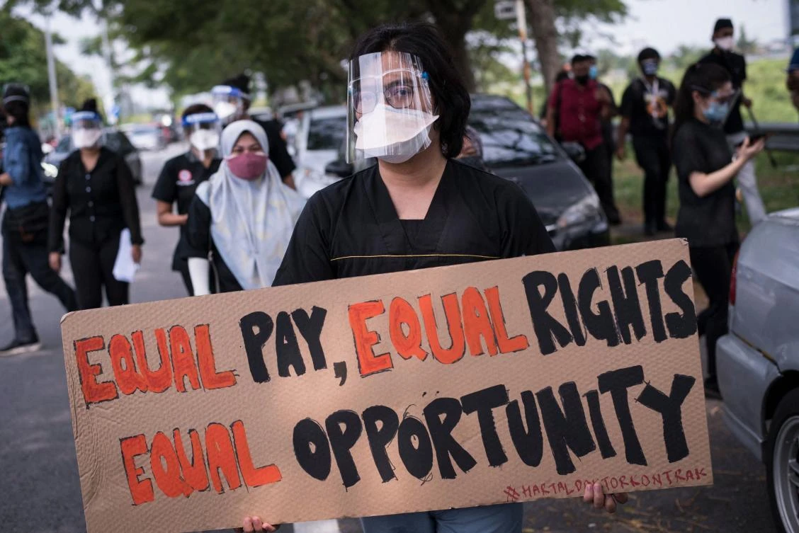 A contract doctor holds a placard during a strike outside the Sungai Buloh Hospital in Selangor state on July 26, 2021. (AFP)