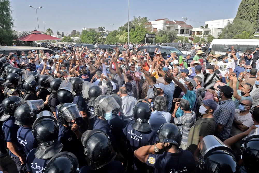 Tunisian security officers hold back protesters outside the parliament building in the capital Tunis on July 26, 2021, following a move by the president to suspend the country’s parliament and dismiss the prime minister. (AFP)
