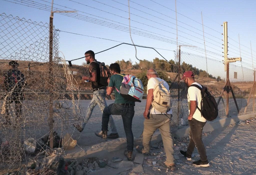 Above, Palestinian workers cross illegaly into Israeli areas through a hole in Israel’s barrier fence near the Mitar checkpoint and the village of Al-Dahriya. (AFP)