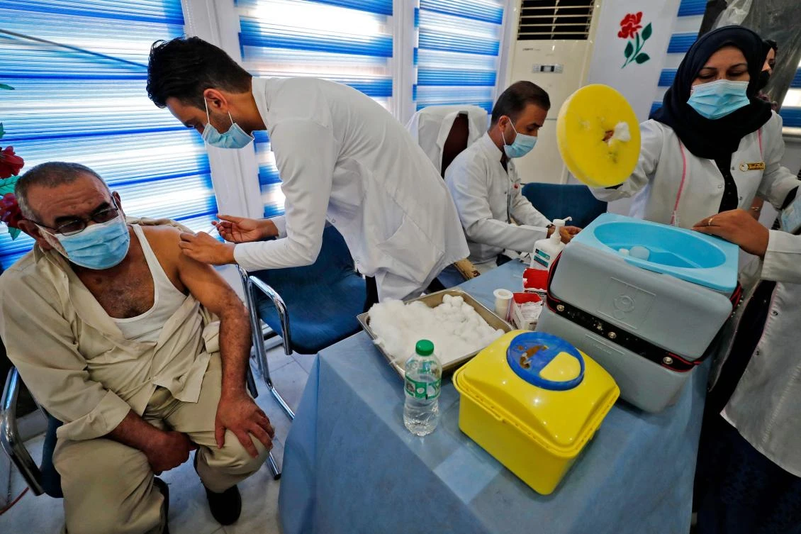 Iraqi medics administer Pfizer-BioNTech COVID-19 vaccine to people at a vaccination center in Baghdad. Over 1.5 million people have now tested positive and 18,347 have officially died of Covid-19 in Iraq. (AFP)
