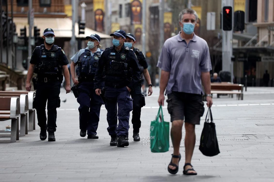 A man walks past police offers patroling the streets of central business district of Sydney on July 31, 2021, as authorities warned against the anti-lockdown protest. (AFP)