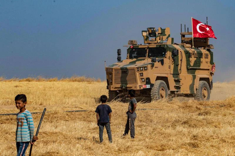 Syrian boys watch as a Turkish military vehicle patrols around the Syrian village of al-Hashisha in Tal Abyad town October 4, 2019. (AFP file)