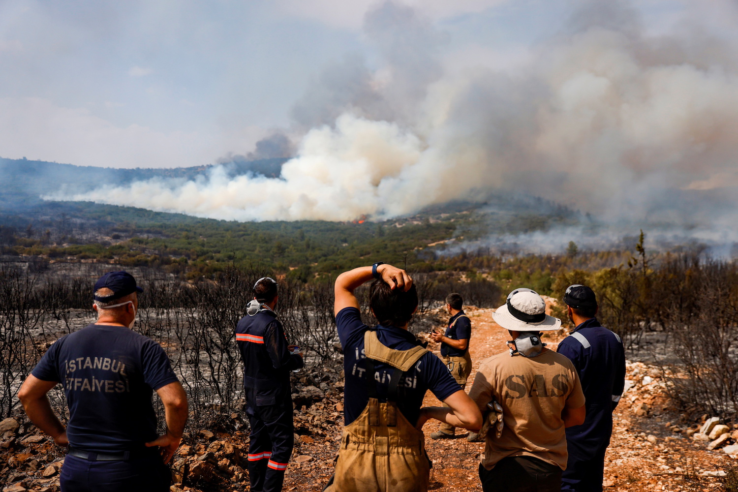Firefighters from Istanbul Municipality and volunteers gather to plan on how to extinguish a wildfire near Ikizce, Turkey on August 6, 2021. (Reuters)
