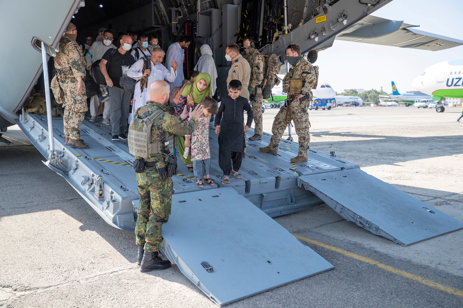 Staff talk to evacuees from Afghanistan as they arrive in an Airbus A400 transport aircraft of the German Air Force Luftwaffe in Uzbekistan. (File/Reuters)