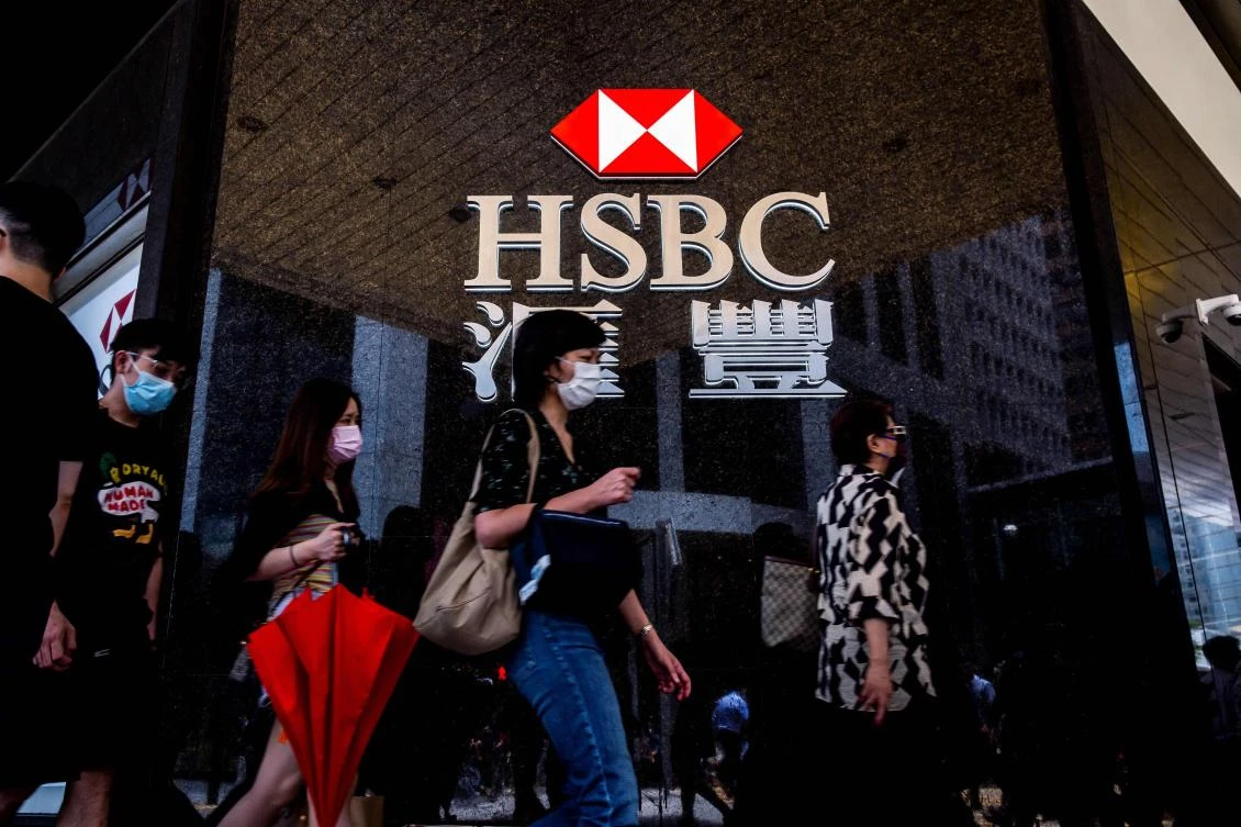 Pedestrians walk past the logo for HSBC outside a local branch bank in Hong Kong on August 2, 2021. (AFP)