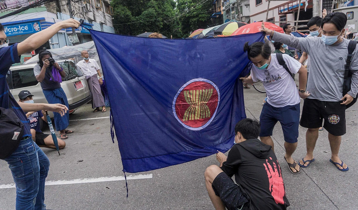 Protesters prepare to burn the flag of the Association of Southeast Asian Nations (ASEAN) grouping, as they take part in a flash mob demonstration against the military coup in Yangon. (AFP)