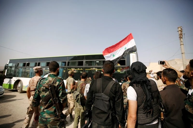 A file photo shows a Syrian Army soldier with a Syrian national flag on his head uses his smartphone as people ride buses to be evacuated from the besieged Damascus suburb of Daraya.(Reuters)