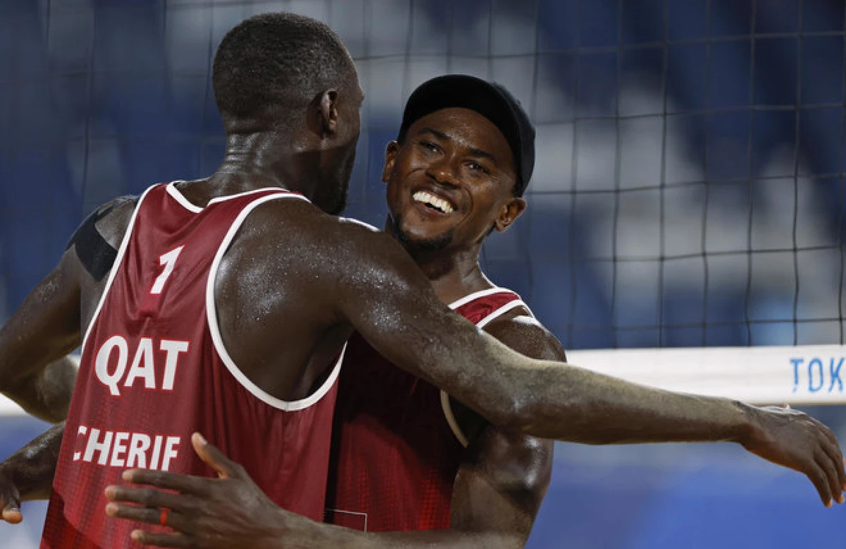Cherif Younousse, right, of Qatar, and teammate Ahmed Tijan, celebrate winning a men's beach volleyball quarterfinal match against Italy on Aug. 4, 2021. (Reuters)