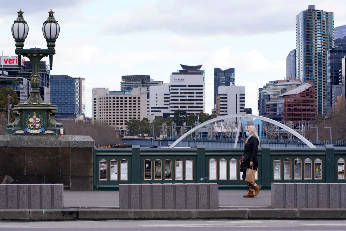 A lone woman walks across an unusually quiet city center bridge on the first day of a lockdown as the state of Victoria looks to curb the spread of a coronavirus disease outbreak in Melbourne. (File/Reuters)