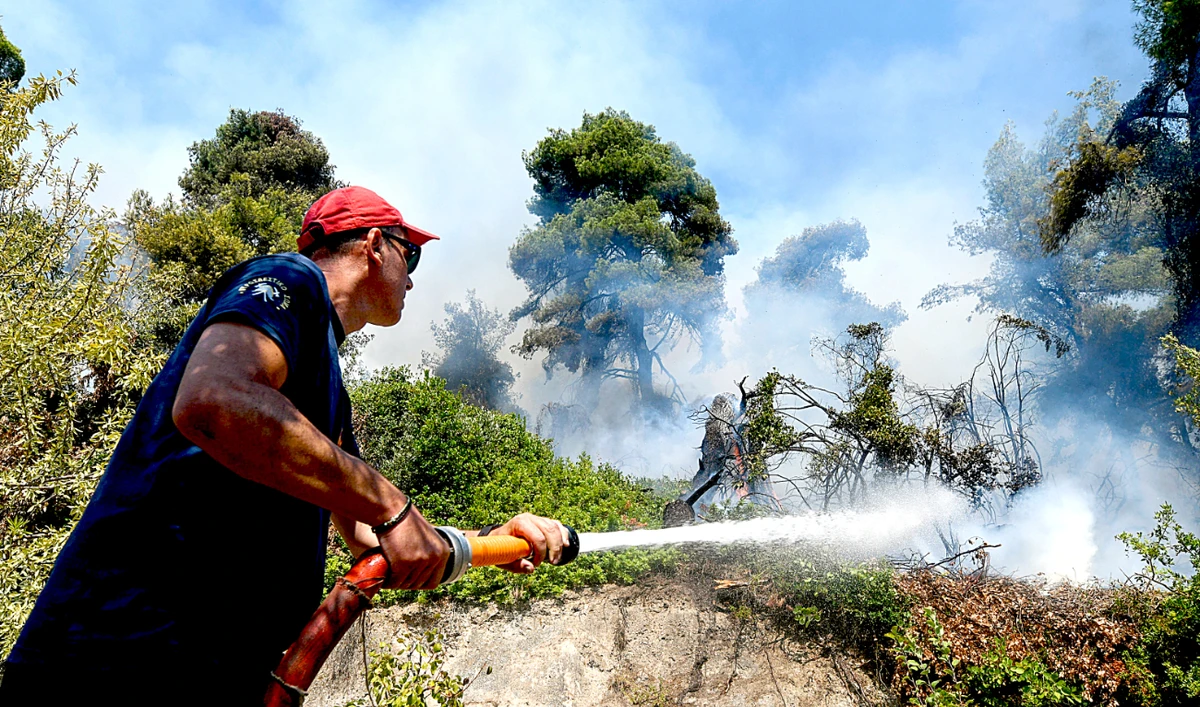 A firefighter tries to extinguish a wildfire burning near the village of Vasilika, on the island of Evia, Greece. (Reuters)