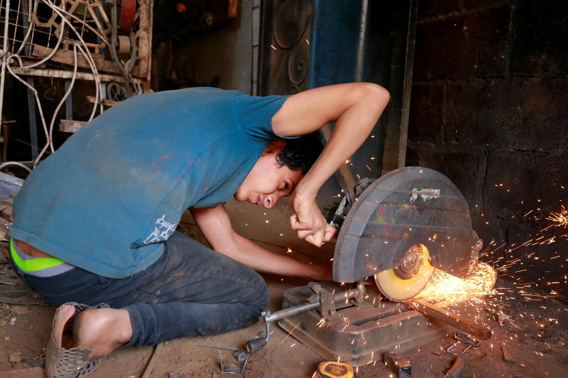 Zakaria Naguib cuts iron bars at a welding workshop in Sanaa, Yemen. (Reuters/Nusaibah Almuaalemi)