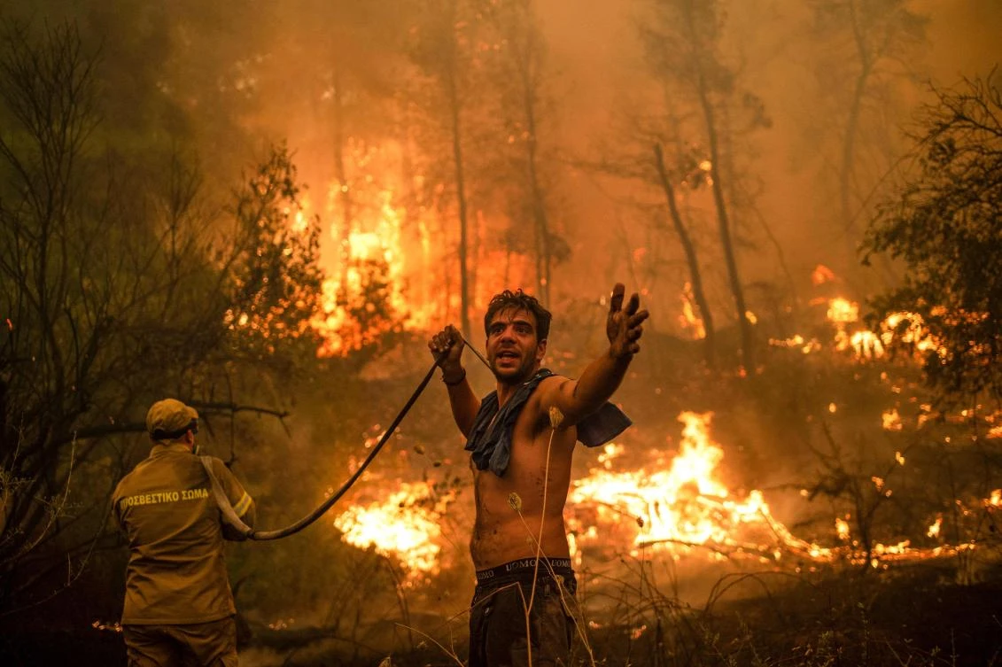 A local resident gestures as he holds an empty water hose during an attempt to extinguish forest fires approaching the village of Pefki on Evia (Euboea) island, Greece’s second largest island on Sunday. (AFP)
