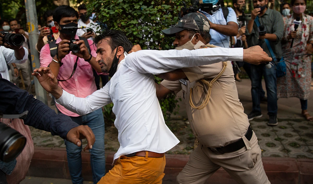 A policeman detains a man from the site of a protest being held against communal violence and violence against minorities, in New Delhi, India, Tuesday, Aug. 10, 2021. (AP)